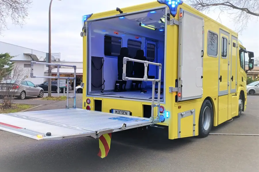 Geöffneter Heckbereich eines gelben Scania-ITW mit ausgeklappter Ladebordwand und sichtbarem Innenraum.