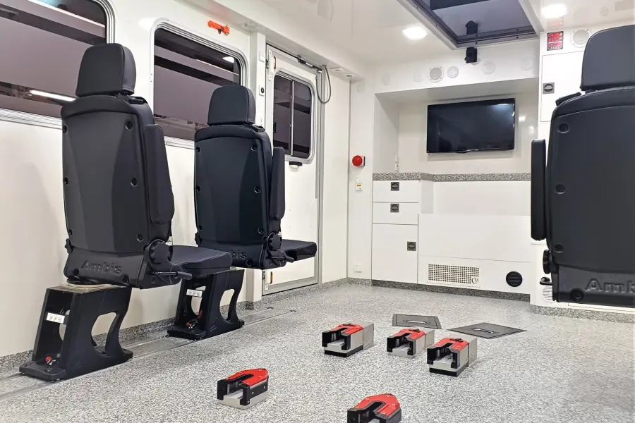 Innenraum eines Scania-Intensivtransportwagens mit Sitzen, Monitor und Tragenverriegelungssystem.