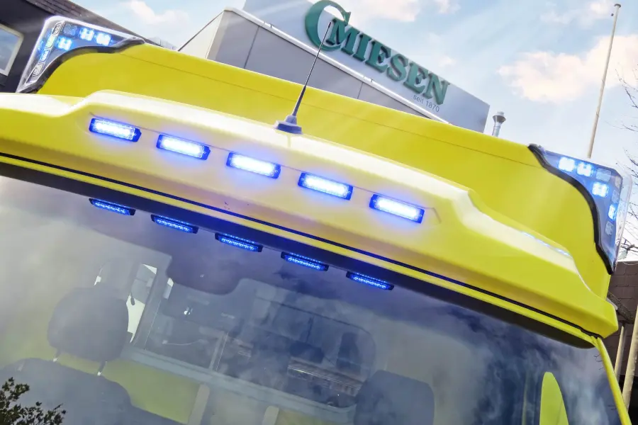 Frontansicht eines gelben Sprinter-ITW mit eingeschaltetem Blaulicht, vor Miesen-Firmengebäude.