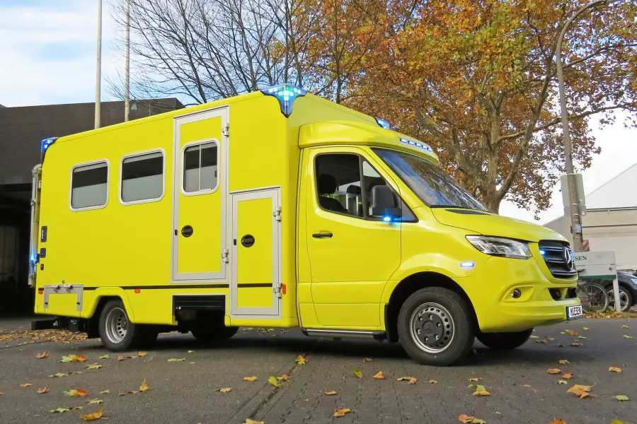 Gelber Mercedes-Benz Sprinter-Intensivtransportwagen (ITW), seitlich von links aufgenommen mit eingeschaltetem Blaulicht.