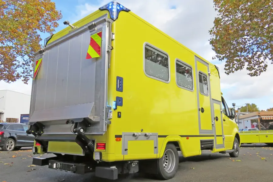 Heckansicht eines gelben Mercedes-Benz Sprinter-ITW mit geschlossener Ladebordwand und Blaulicht.