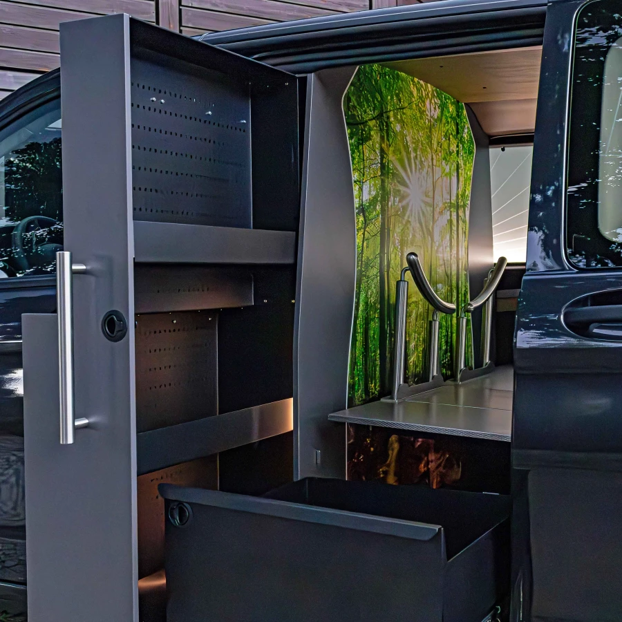 Innenansicht eines Fahrzeugs mit modernem Stauraum und beleuchteter Tragefläche vor einer Walddekorwand.