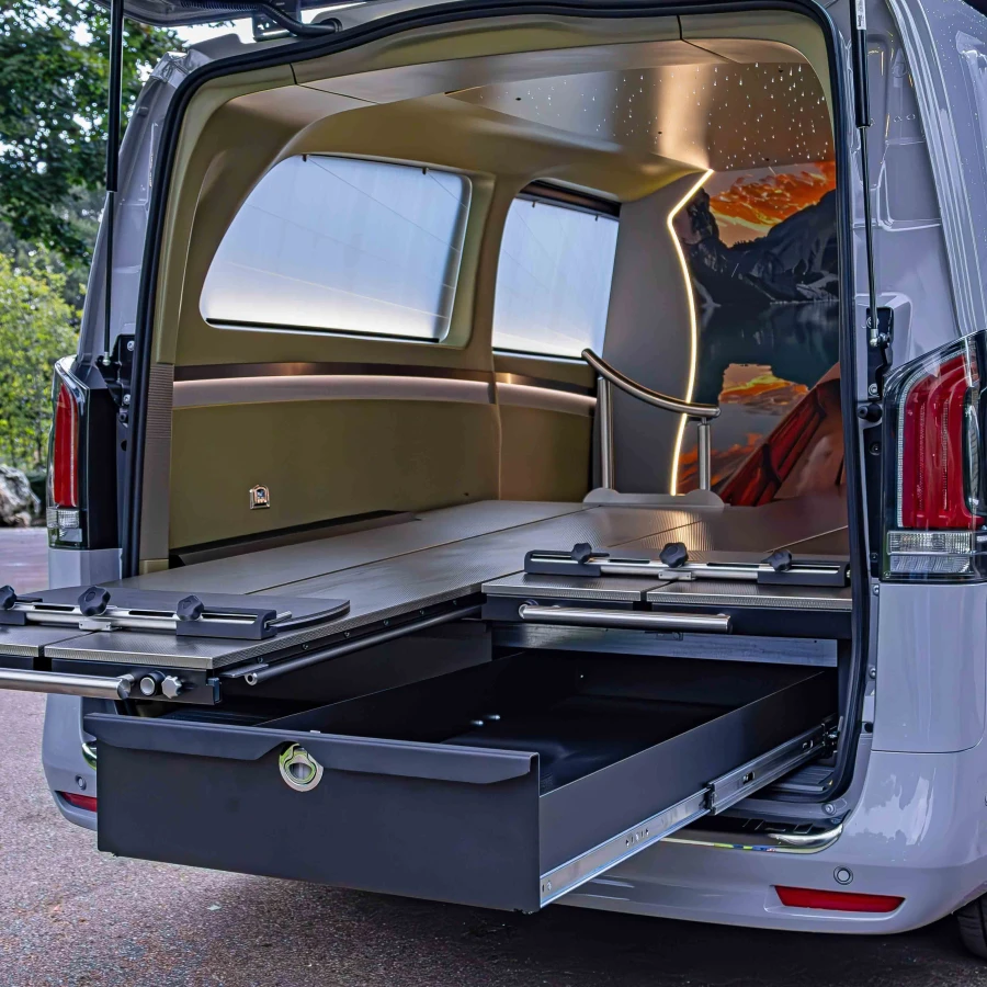 Innenraum eines Fahrzeugs mit ausziehbarer Plattform und beleuchtetem Deckenhimmel vor Landschaftsmotiv.