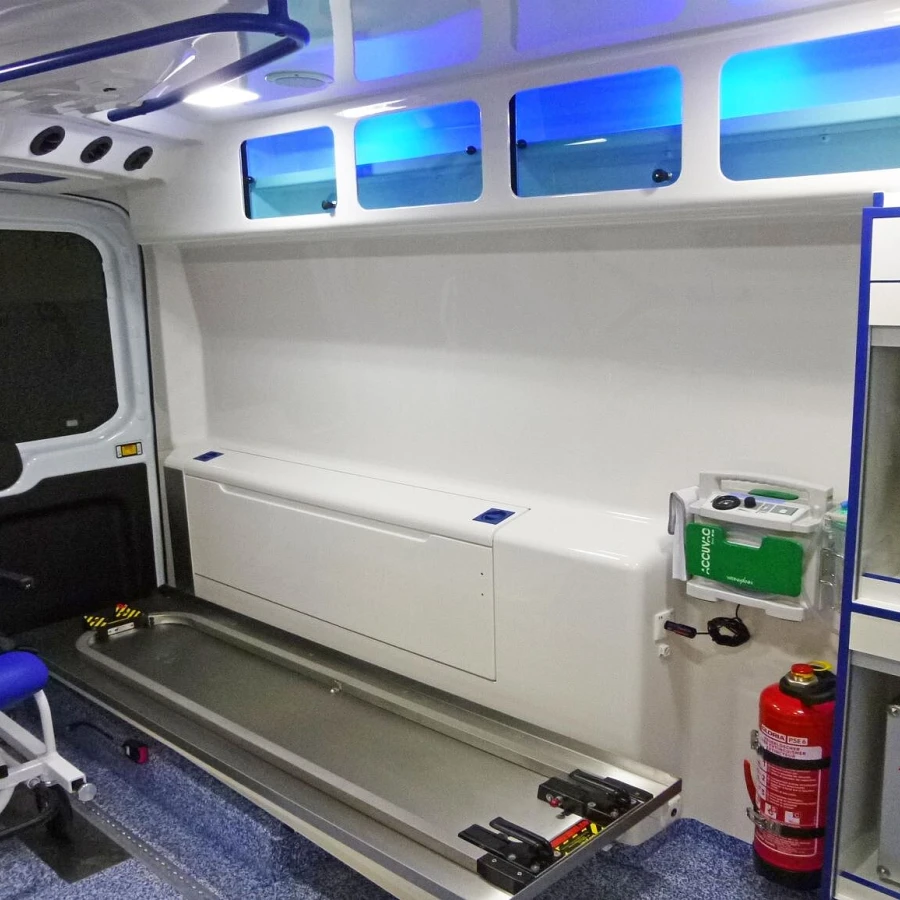 Innenraum eines modernen Krankentransportwagens mit blauer LED-Beleuchtung, Sitzplatz und medizinischer Ausstattung.