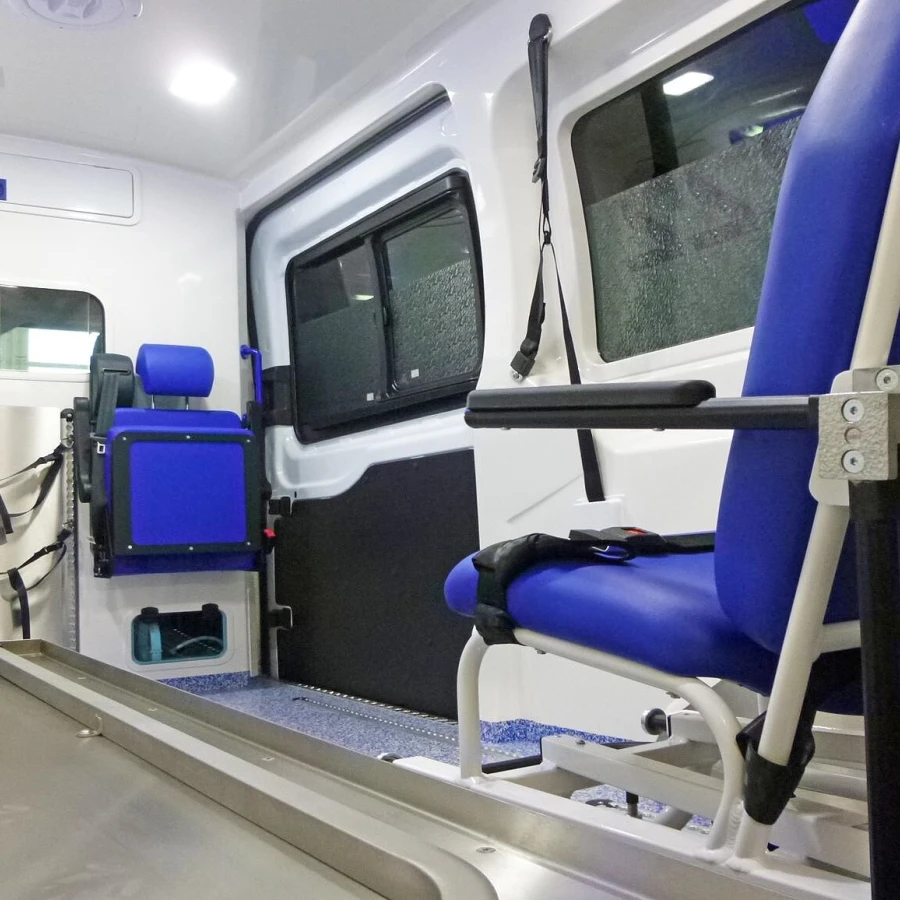 Innenraum eines Krankentransportwagens mit blauen Sitzen, Halterungen und einer Liegefläche für den Transport von Patienten.