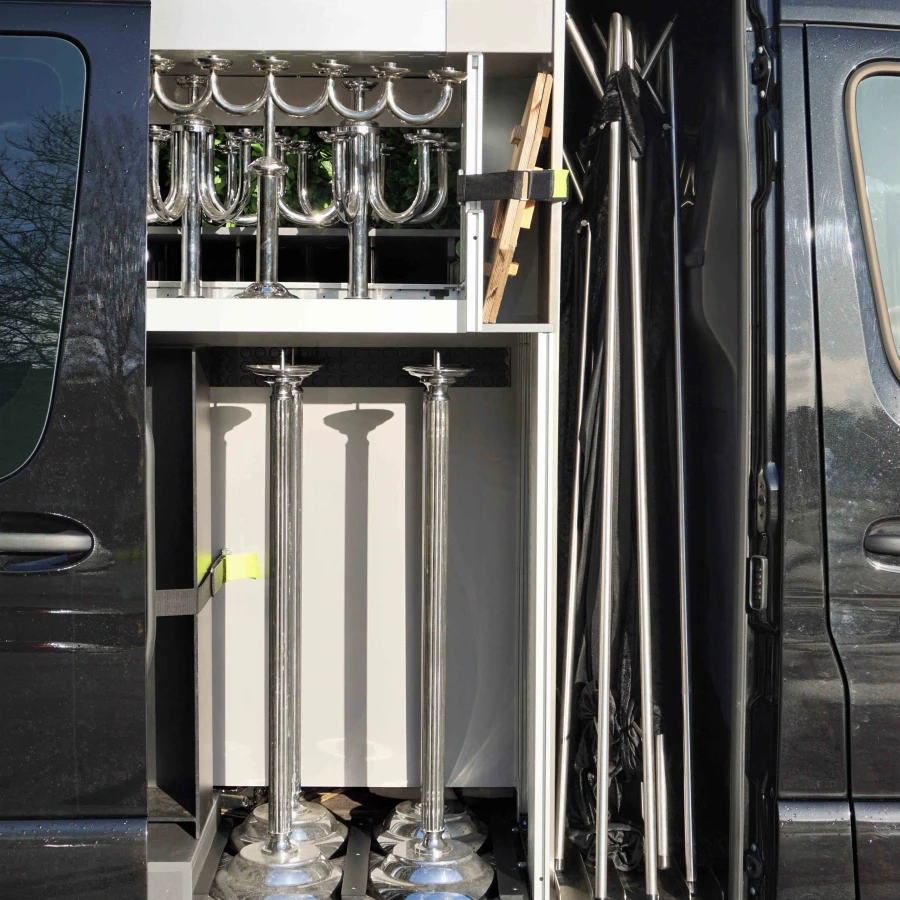 Detailansicht des Innenausbaus eines schwarzen Transporters mit silbernen Halterungen und glänzenden Metallständern.