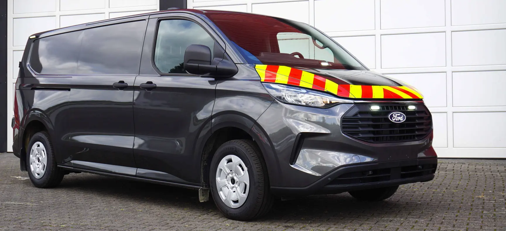 Bestattungswagen mit Kühltechnik und eingeschalteten weißen Blitzleuchten im Kühlergrill und hinter der Windschutzscheibe