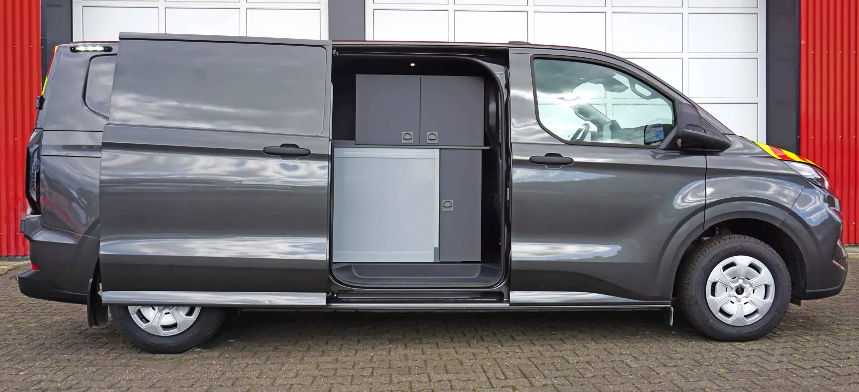 Grauer Transporter mit geöffneter Seitentür und sichtbarem Stauraum im Innenbereich.