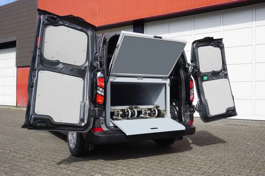 Offene Heckansicht eines schwarzen Fahrzeugs mit ausziehbarem Fach und integrierter Technik im Laderaum.