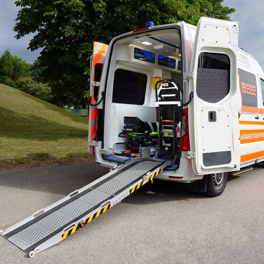 Krankentransportwagen mit geöffneter Hecktür und ausgeklappter Rampe zur Beladung.