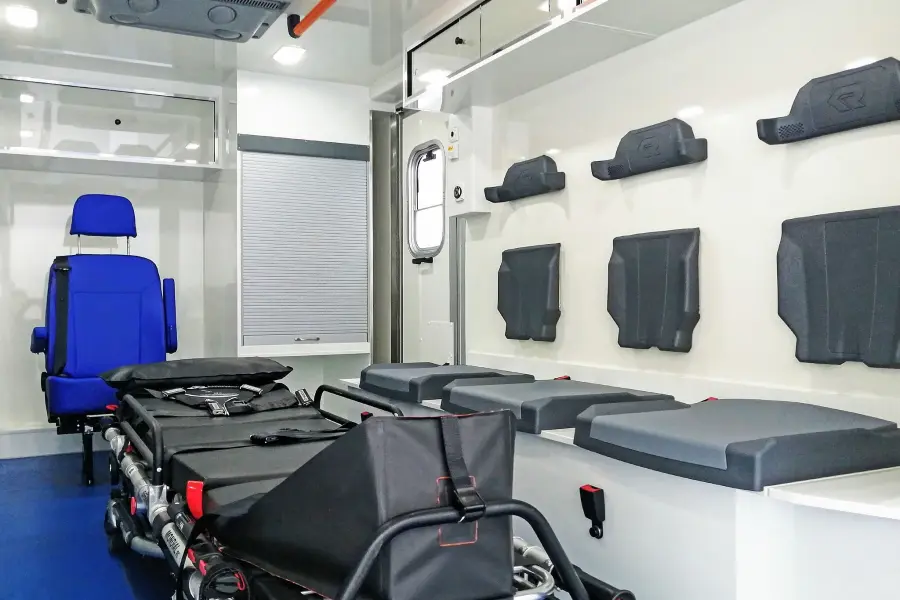 Innenraum eines RTW mit Trage, blauen Sitzen und Stauraum.
