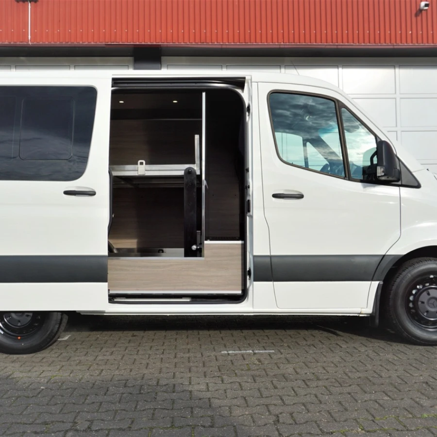 Seitenansicht eines weißen Fahrzeugs mit geöffneter Schiebetür und Holzverkleidung im Innenraum.