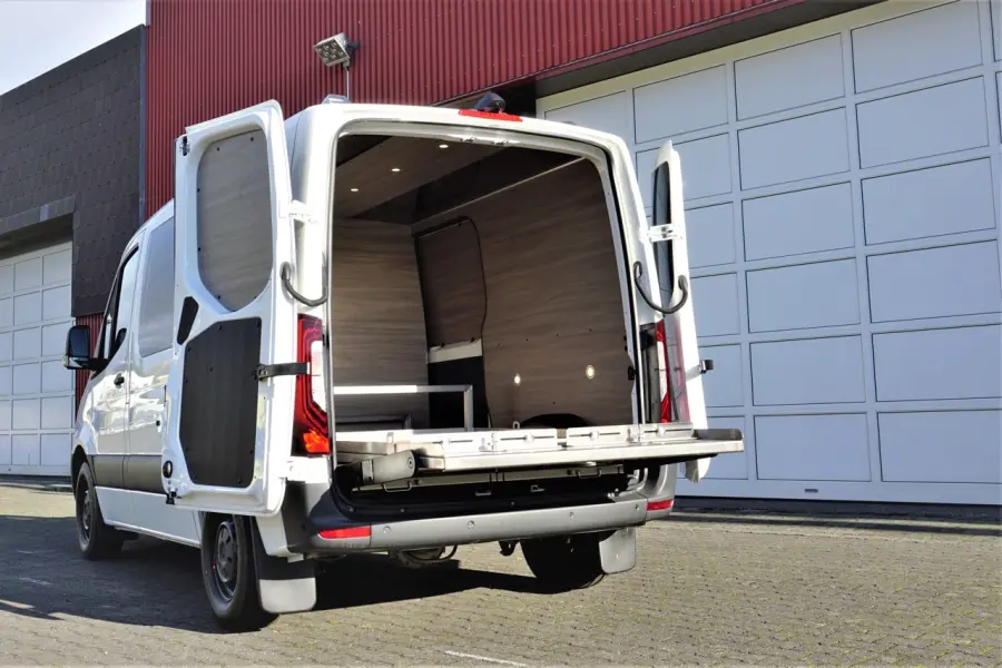 Heckansicht eines weißen Bestattungsfahrzeugs mit geöffneter Ladefläche und modernem Innenausbau in Holzoptik.