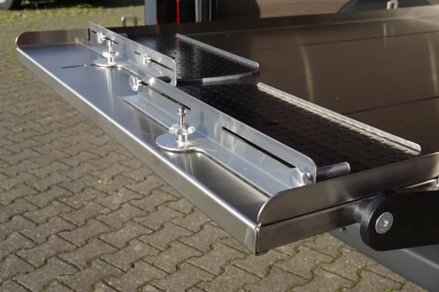 Detailaufnahme einer ausziehbaren Edelstahlplattform mit Halterungen im Fahrzeugheck.