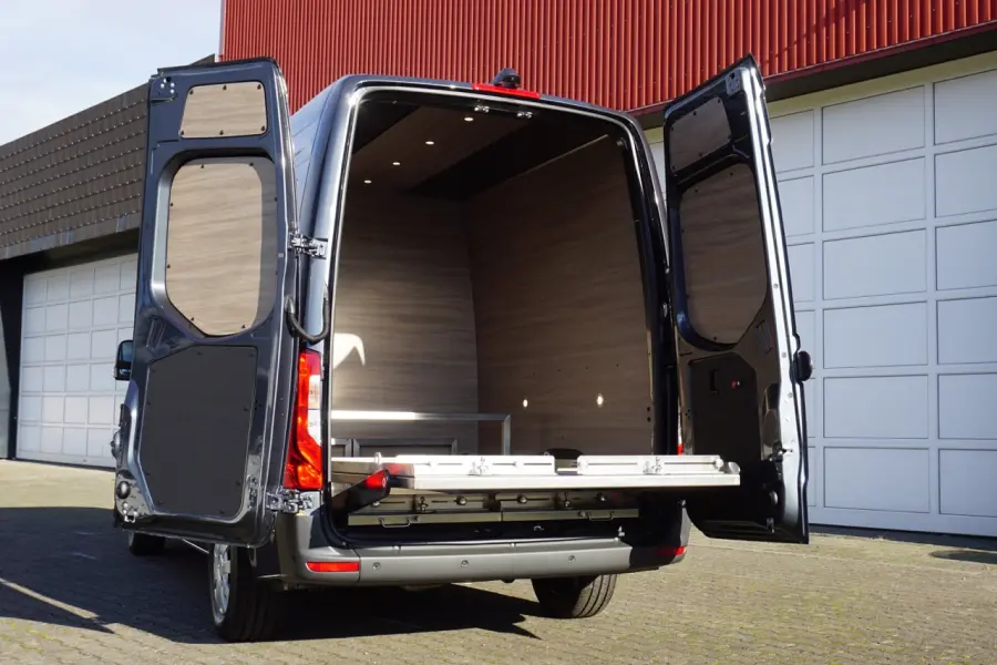 Geöffnete Hecktüren eines schwarzen Fahrzeugs mit hellem Holzinterieur und ausziehbarer Trage im Laderaum.