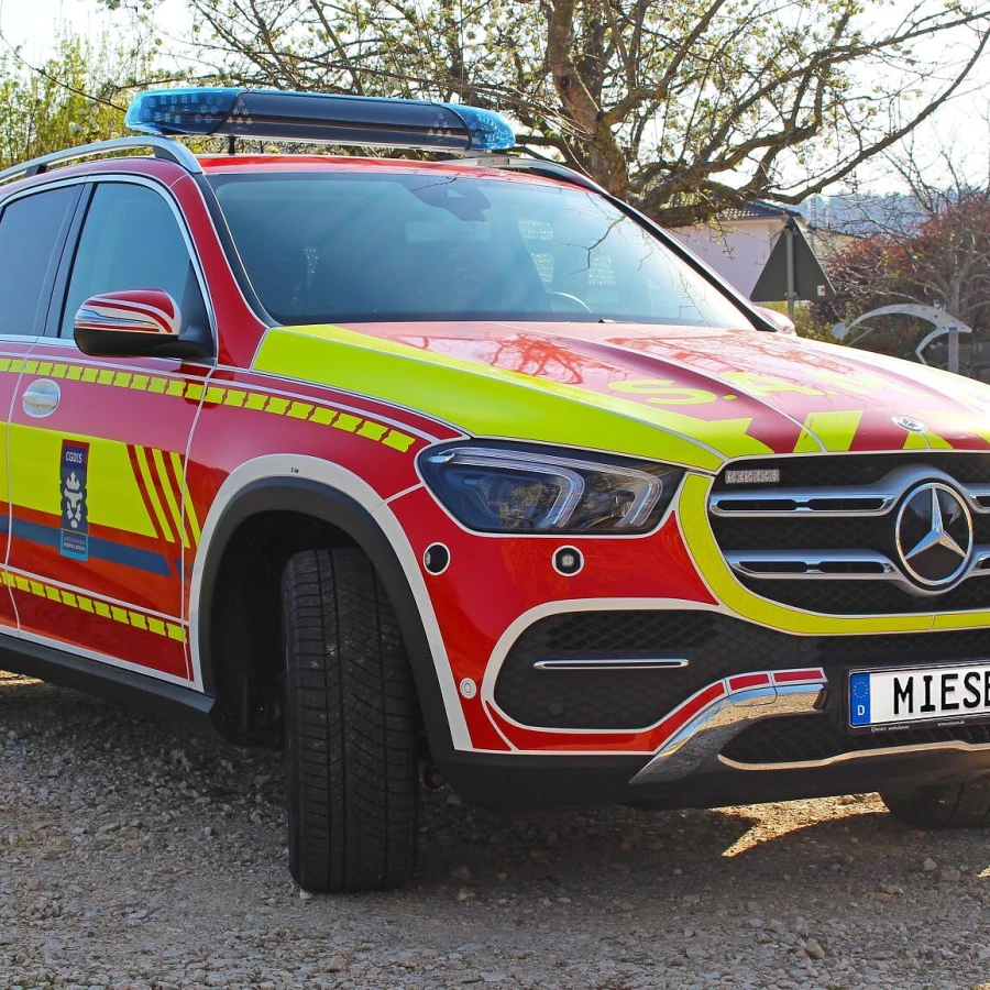 Notarzteinsatzfahrzeug auf Mercedes-Benz-Basis mit roter und gelber Beklebung sowie Blaulichtbalken auf dem Dach.
