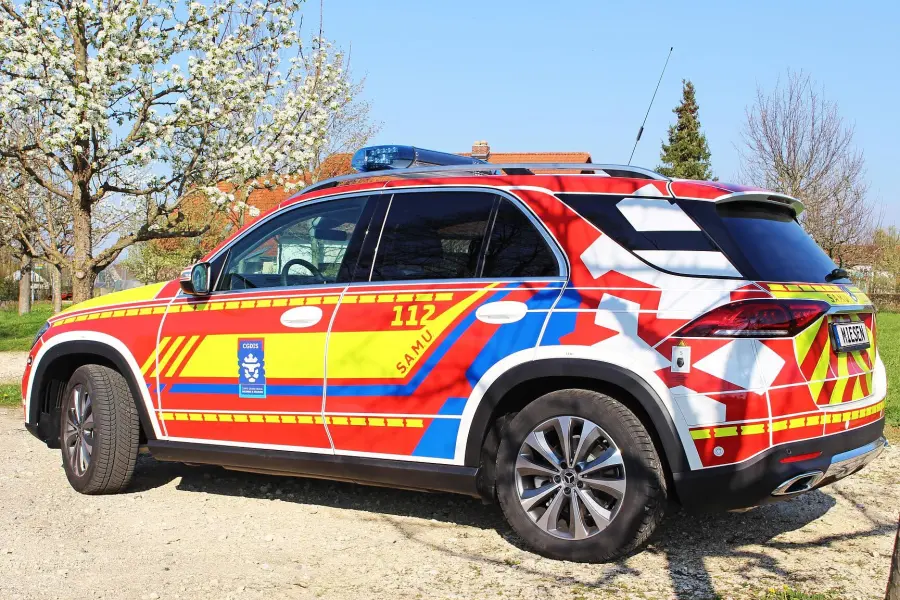 Seitenansicht eines farbenfroh beklebten Notarzteinsatzfahrzeugs mit der Kennzeichnung „SAMU“ und der Notrufnummer 112.