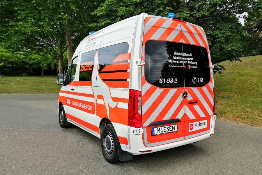 Heckansicht eines Krankentransportwagens der Malteser mit auffälliger rot-weißer Warnbeklebung.