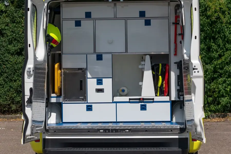 Blick in das geöffnete Heck eines gelben Notarztfahrzeugs mit organisiertem Stauraum und Schubladensystem für medizinische Ausrüstung.