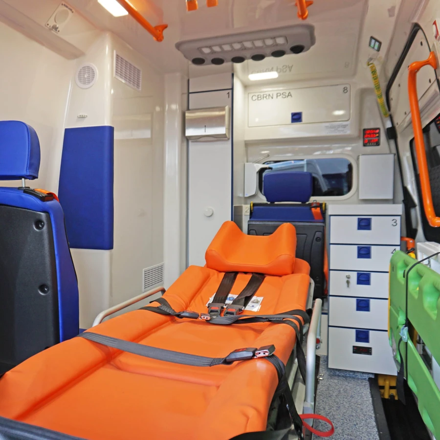 Innenraum eines KTW B mit oranger Trage, blauen Sitzen und grüner Tragehalterung an der Wand.