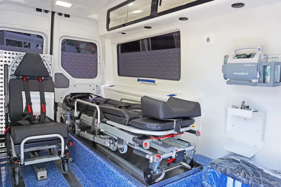 Innenraum eines modernen Krankentransportwagens mit Trage, Sitzplatz für Begleitperson und medizinischer Ausstattung.