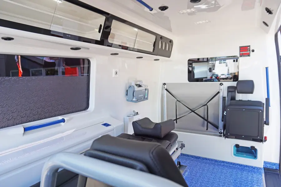 Innenraum eines modernen Krankentransportwagens mit Trage, Sitzplätzen und medizinischer Ausstattung.