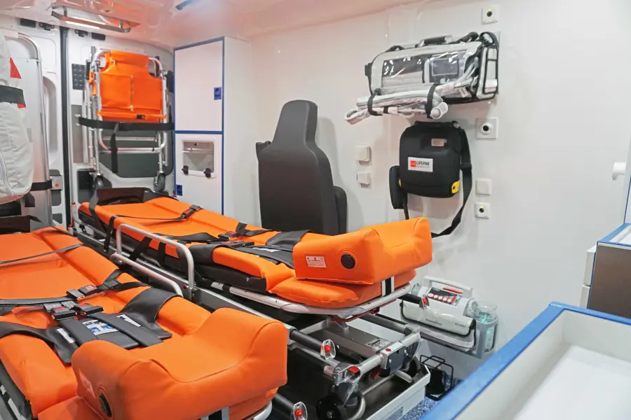Innenraum eines Rettungswagens mit zwei orangefarbenen Krankentragen, medizinischen Geräten und Stauraum für Notfallausrüstung.