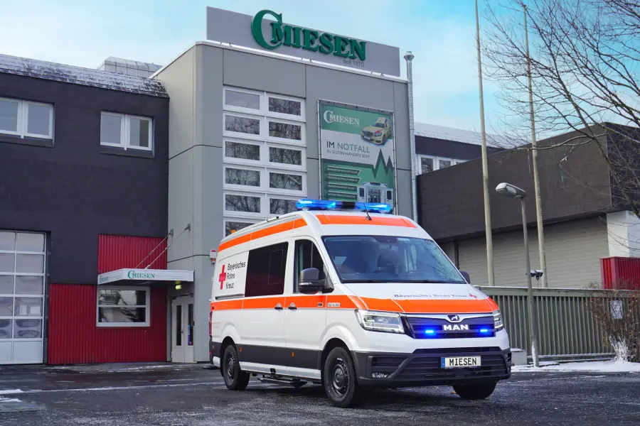 KTW des Bayerischen Roten Kreuzes auf MAN-Basis mit orange-weißer Lackierung und Blaulicht, aufgenommen vor dem Miesen-Firmensitz bei winterlichen Bedingungen.