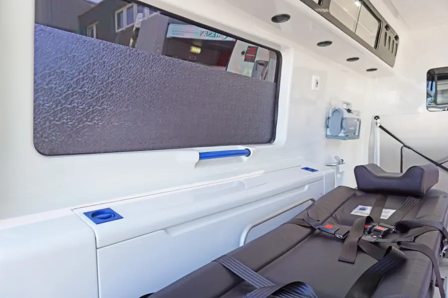 Innenraum eines KTW mit Trage, Stauraum und abgedunkeltem Fenster.