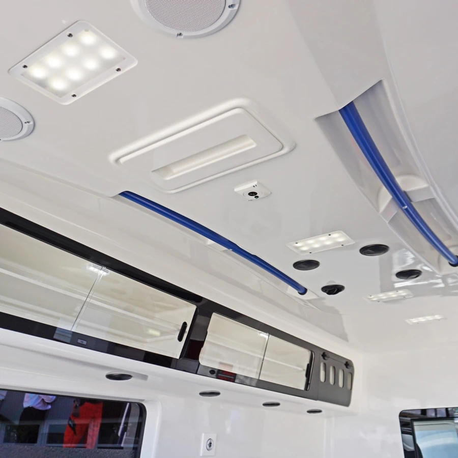 Deckenansicht im Inneren eines Krankentransportwagens mit LED-Leuchten, Lautsprechern, Halteschienen und Stauraumklappen.