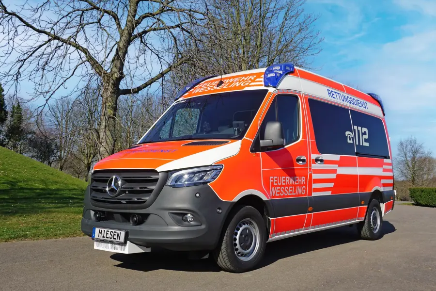 TW der Feuerwehr Wesseling auf Mercedes-Benz Sprinter-Basis mit Hochdach, auffälliger rot-weißer Beklebung und Blaulichtanlage.