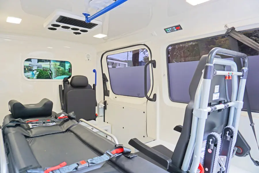 Innenraum eines Krankentransportwagens mit Trage, Sitzplätzen und moderner Innenausstattung.
