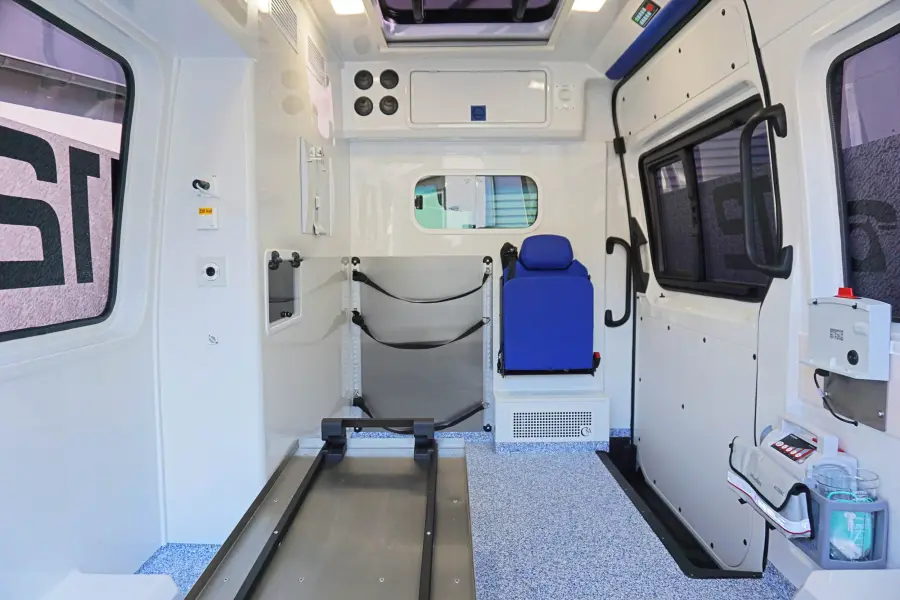Innenraum eines modernen Krankentransportwagens mit Tragenführungssystem, blauer Sitzbank und hygienischer Ausstattung.