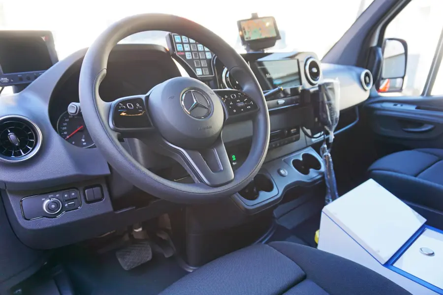 Fahrerkabine eines Mercedes-Fahrzeugs mit moderner Bedieneinheit und Kommunikationsausstattung.
