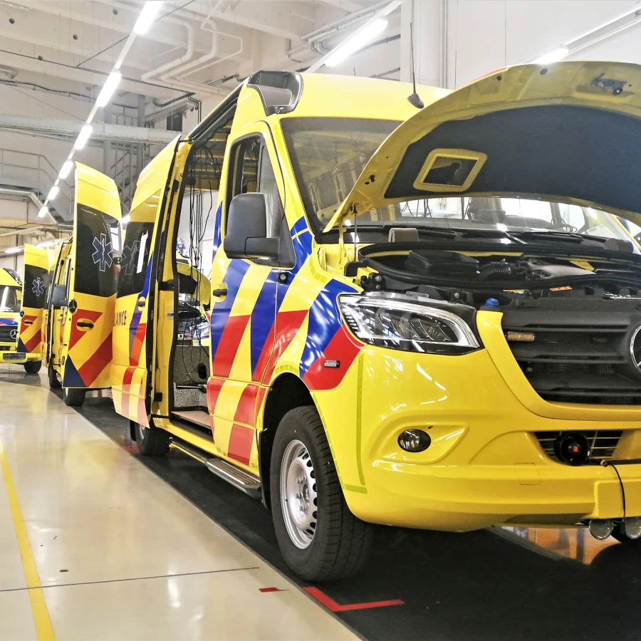 Mehrere gelbe Rettungswagen in einer Produktionshalle bei offener Wartung