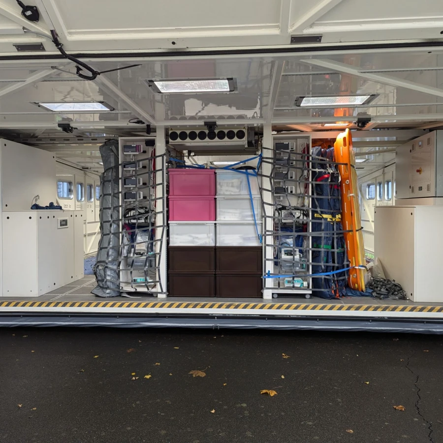 Innenraum eines Katastrophenschutz-Containers mit medizinischer Ausrüstung und gesicherten Lagerfächern.