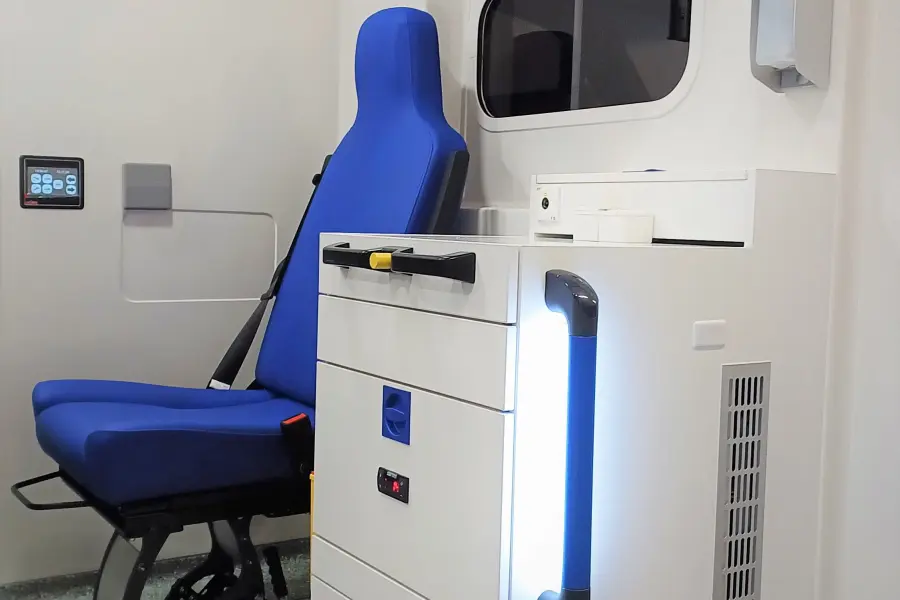 Innenansicht eines Rettungswagens mit blauem Sitz, Stauraum und medizinischer Ausstattung.