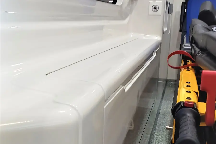 Detailansicht einer Seitenwand im Inneren eines Rettungswagens mit Fenster, Versorgungsanschlüssen und Staufach.