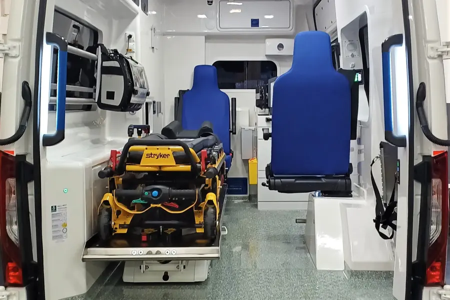 Blick in das geöffnete Heck eines modernen Rettungswagens mit Trage, blauen Sitzen und medizinischer Ausrüstung.