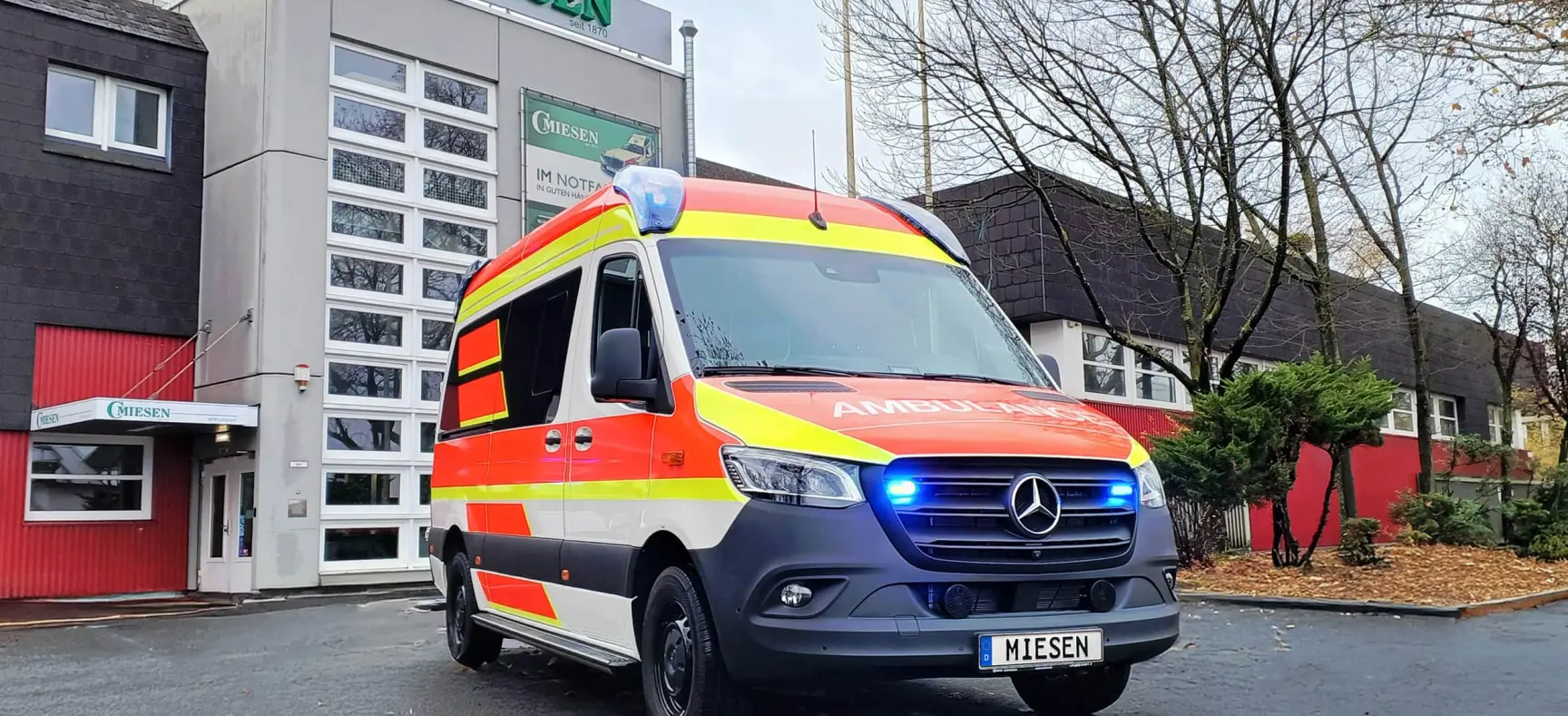 Rettungswagen mit eingeschaltetem Blaulicht vor dem Firmengebäude von C. Miesen.