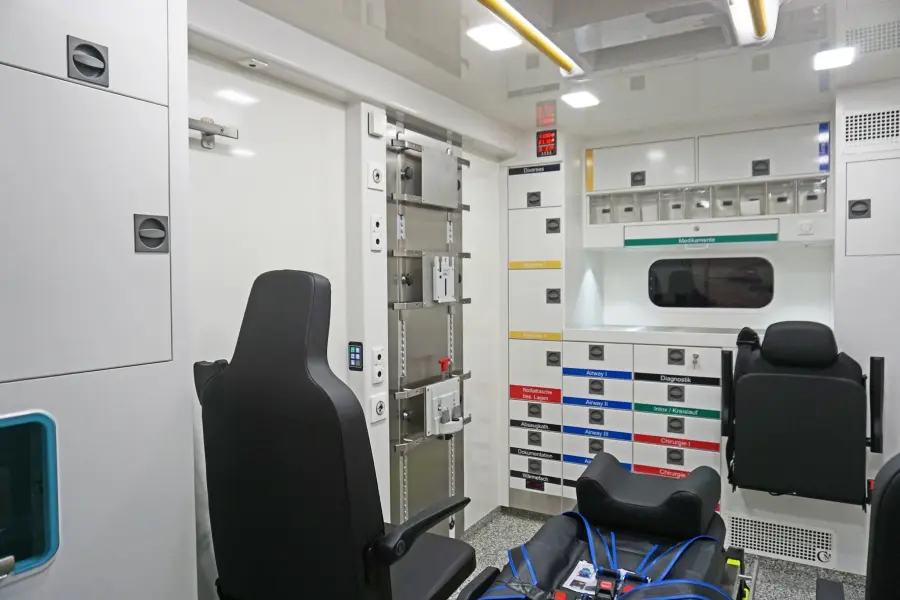 Innenansicht eines hochmodernen Rettungswagens mit strukturierter Schrank- und Schubladenanordnung.