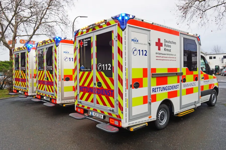 Drei Rettungswagen des DRK Main-Kinzig-Kreis mit auffälliger Heckbeklebung und eingeschaltetem Blaulicht.