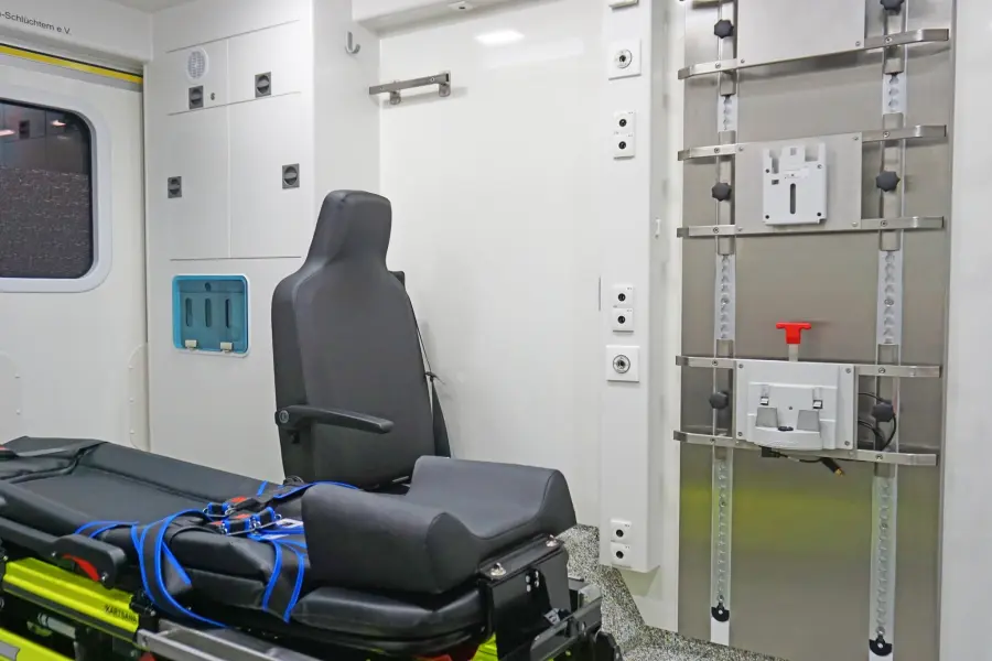 Innenansicht eines Rettungswagens mit Sitzplatz, Trage und medizinischer Gerätehalterung.