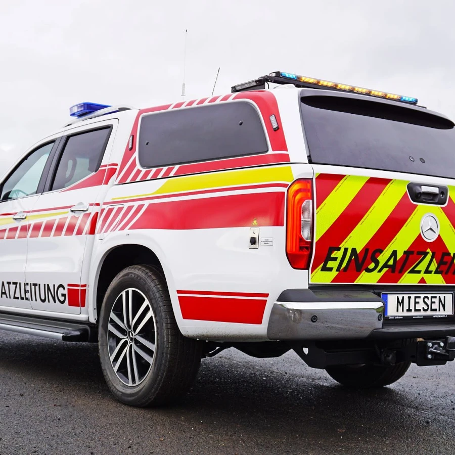 Einsatzleitfahrzeug der Feuerwehr mit gelb-roter Heckwarnbeklebung und MIESEN-Kennzeichen.