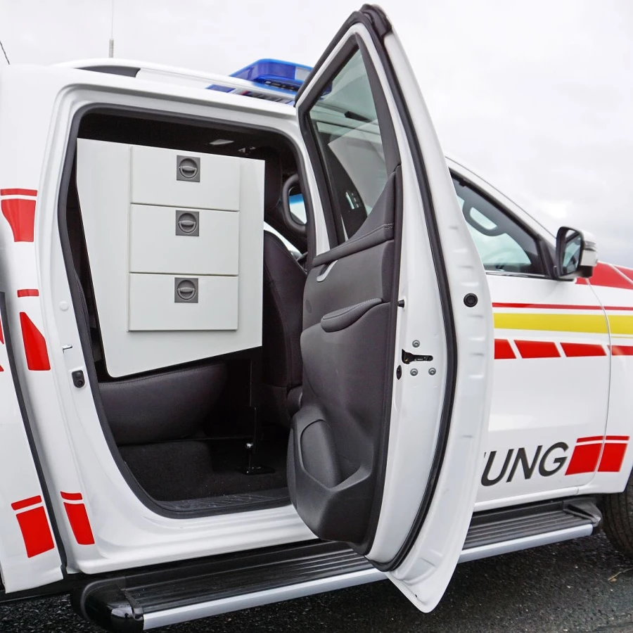 Seitliche Aufnahme eines Einsatzfahrzeugs mit geöffneter Tür und integriertem Schubladensystem im Innenraum.